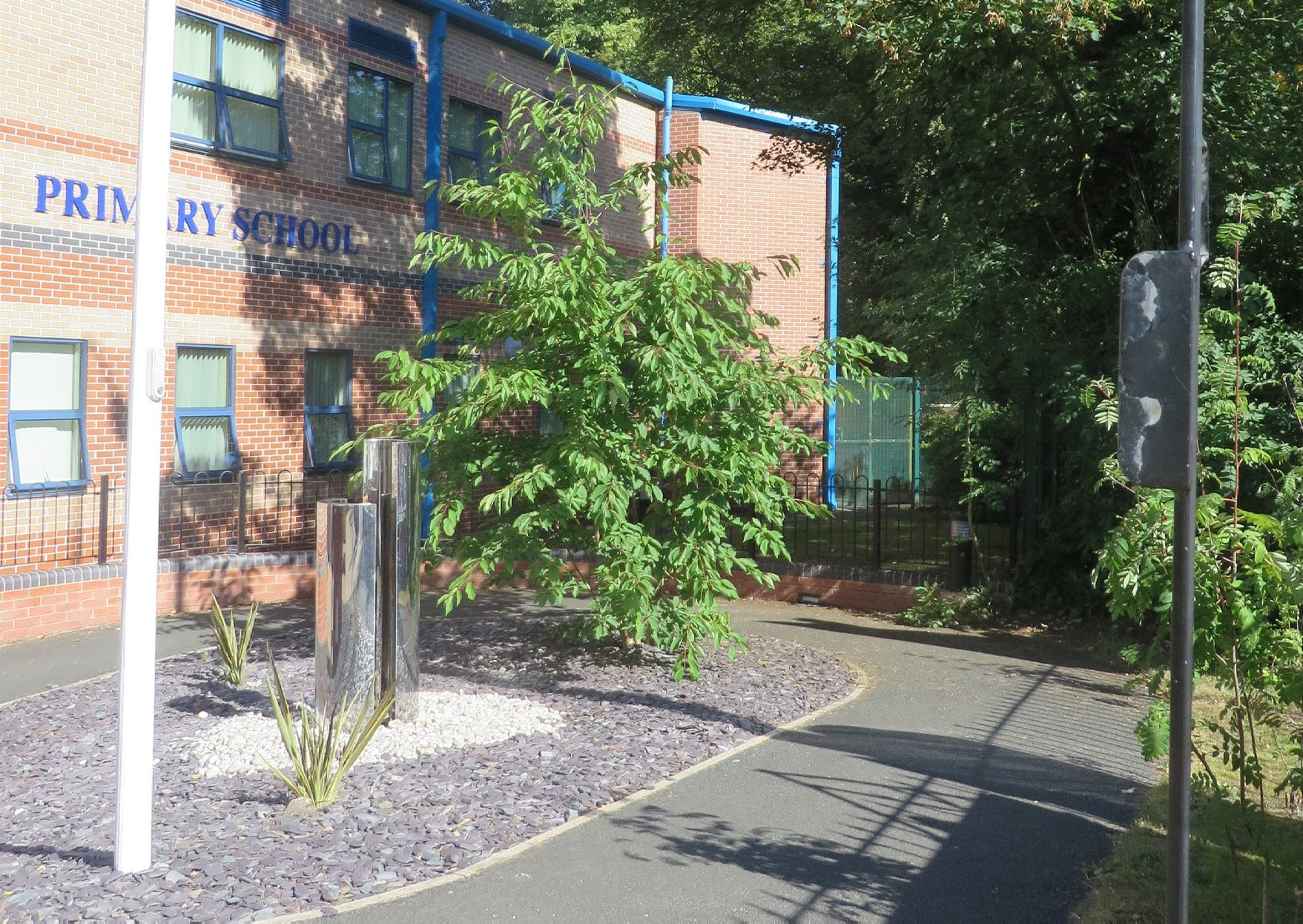 Completed primary school frontage with new planting beds, signage and a paved arrival area.
